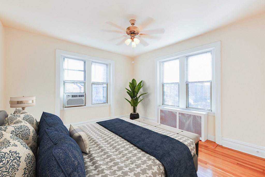 bedroom with bed, nightstand, hardwood floors, ceiling fan and large windows at chatham courts apartments in washington dc