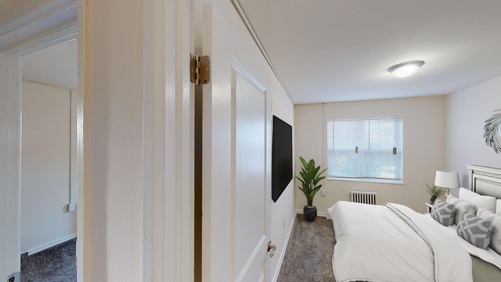 bedroom with bed, nightstand, tv, window and lighting at manor village  tax credit apartments in washington dc