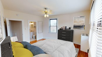 bedroom with bed, dresser, closet and view of bathroom at the klingle apartments in washignton dc - Photo Gallery 5