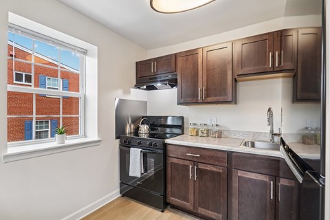 A kitchen with a black stove top oven and brown cabinets.