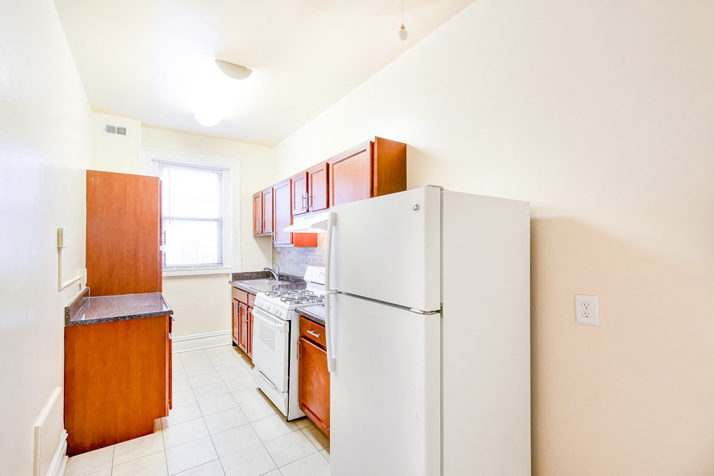 kitchen with tile flooring, white appliances and oak cabinetry at chatham courts apartments in washington dc