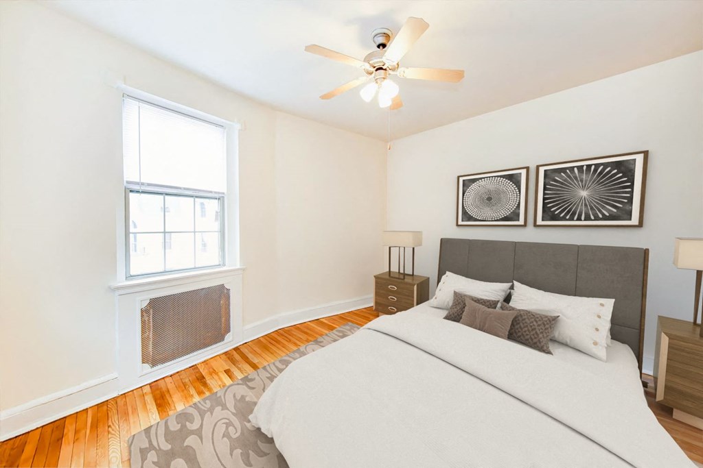bedroom with bed, nightstand, ceiling fan and  large window at 2800 ontario road apartments in washington dc