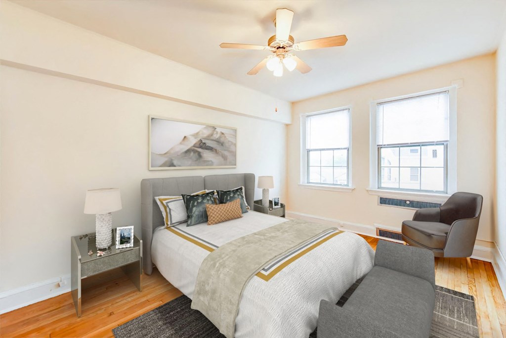 bedroom with bed, nightstand, hardwood floors, ceiling fan and large windows at 2800 ontario road apartments in washington dc