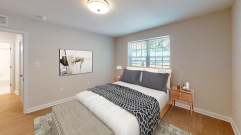 A bedroom with a bed, nightstand, and a painting on the wall.