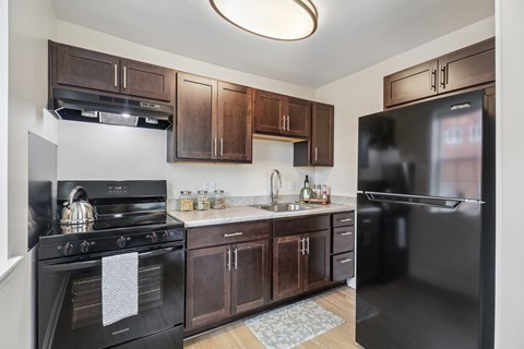A kitchen with black appliances and wooden cabinets.