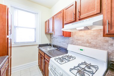 kitchen with tile backsplash, modern cabinetry, gas range and window at chatham courts apartments in washington dc