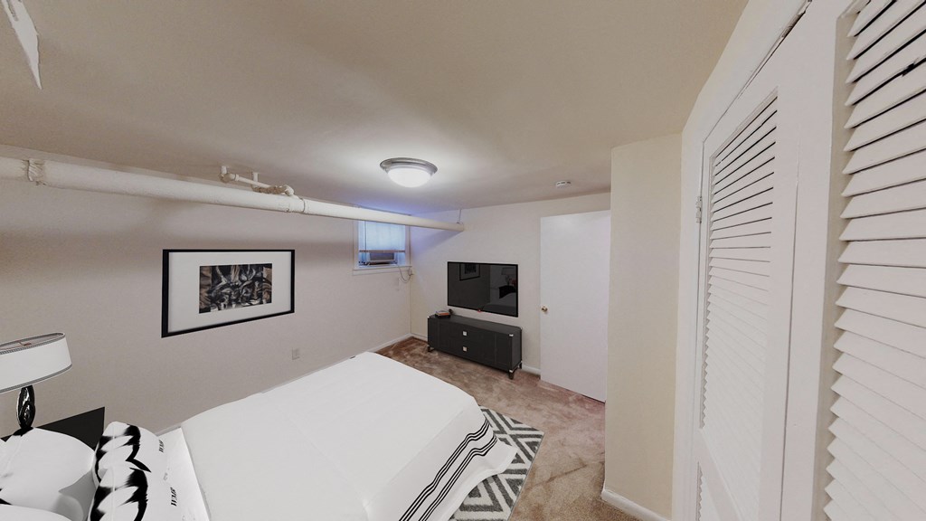 bedroom with bed, plush carpeting, dresser and tv at 1818 riggs apartments washington dc