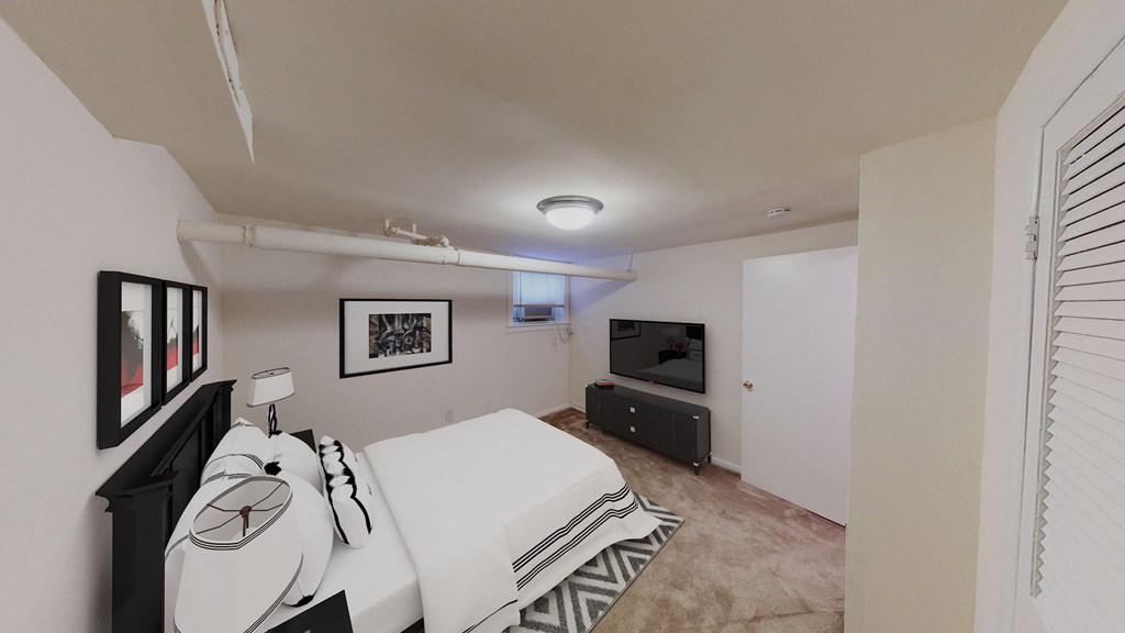 bedroom with bed, plush carpeting, dresser and tv at 1818 riggs apartments washington dc