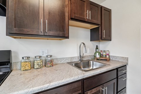 A kitchen with a marble countertop and wooden cabinets.