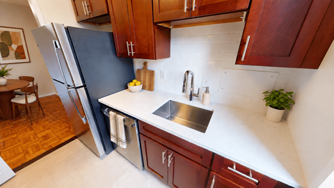 A kitchen with a refrigerator, sink, and cabinets.