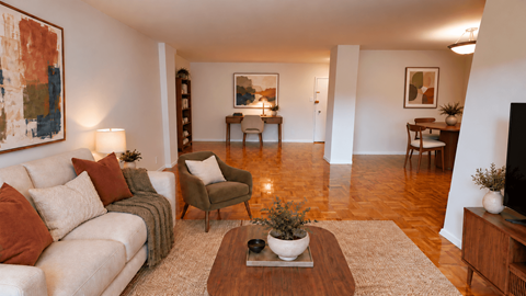 A living room with a white couch, a brown armchair, and a coffee table with a plant on it.