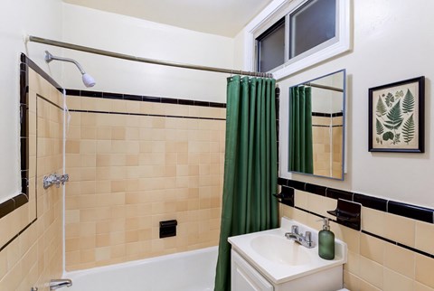 A bathroom with a green shower curtain and a white sink.