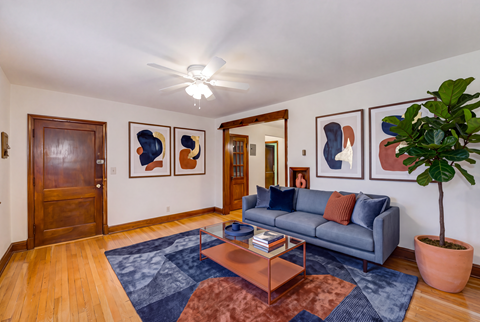 A living room with a grey couch, a coffee table, and three framed artworks on the wall.
