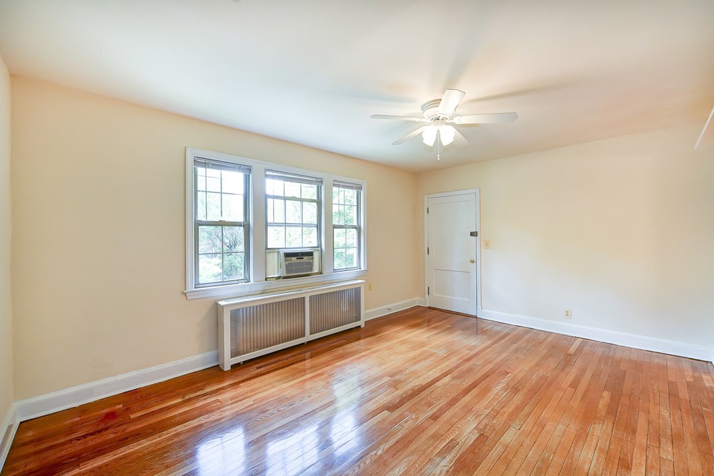 vacant living area with hardwood flooring, ceiling fan, and large windows  at  2629 39th Street apartments in washington dc