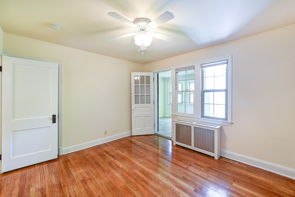 vacant bedroom with hardwood flooring, ceiling  fan and large windows  at  2629 39th Street apartments in washington dc
