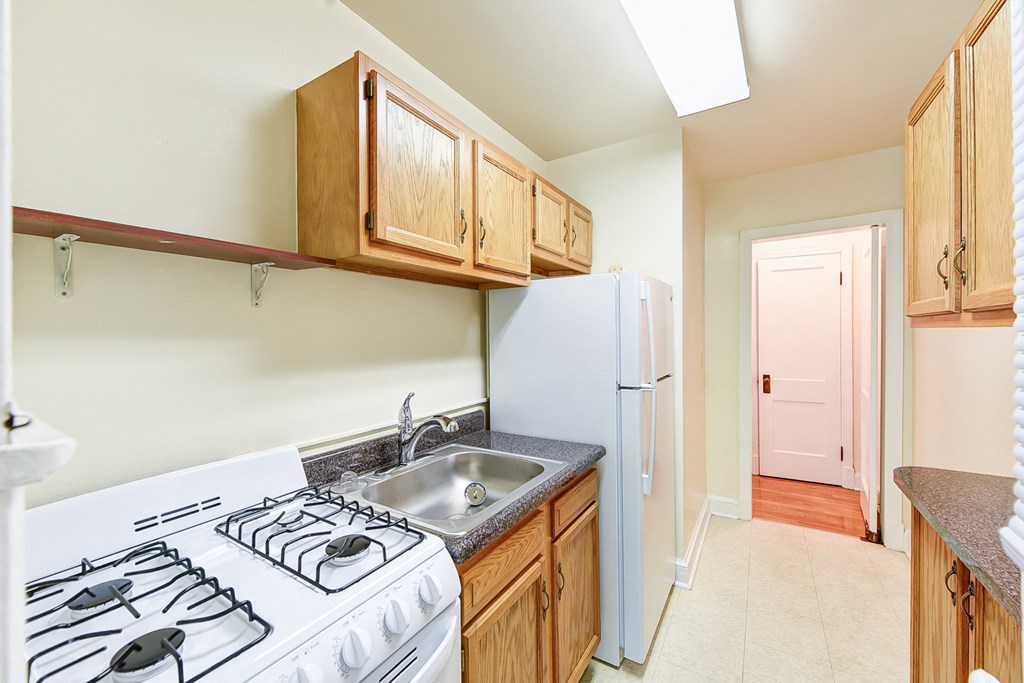 kitchen with tile flooring, wood cabinetry, energy efficient appliances and view to hallway at  2629 39th Street apartments in washington dc
