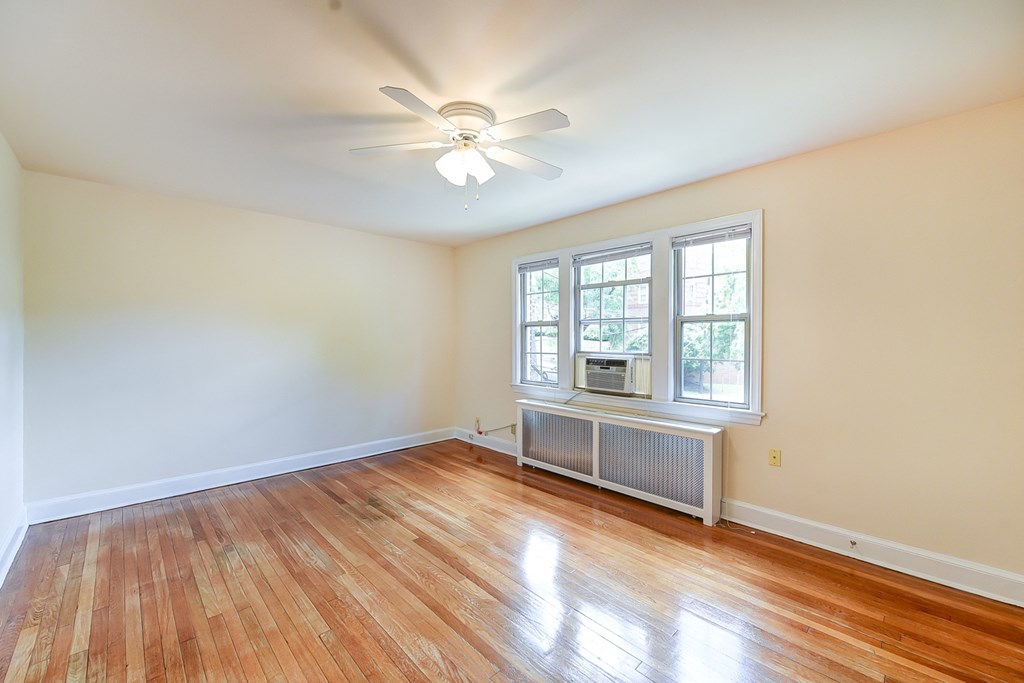 vacant living area with hardwood flooring, ceiling fan, and large windows  at  2629 39th Street apartments in washington dc