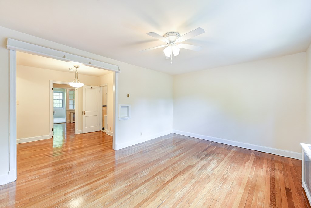 vacant living area with hardwood floors, celing fan and view of hallway and sunroom  at  2629 39th Street apartments in washington dc