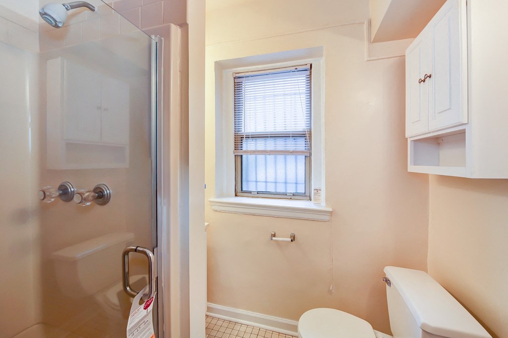 bathroom with walk in shower, vanity, large mirror, tile details and window at 2800 ontario road apartments in washington dc