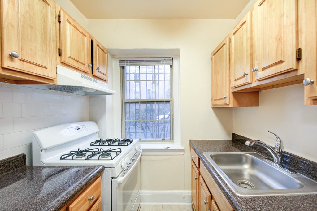 kitchen with tile flooring, white appliances and oak cabinetry at 2800 ontario road apartments in washington dc