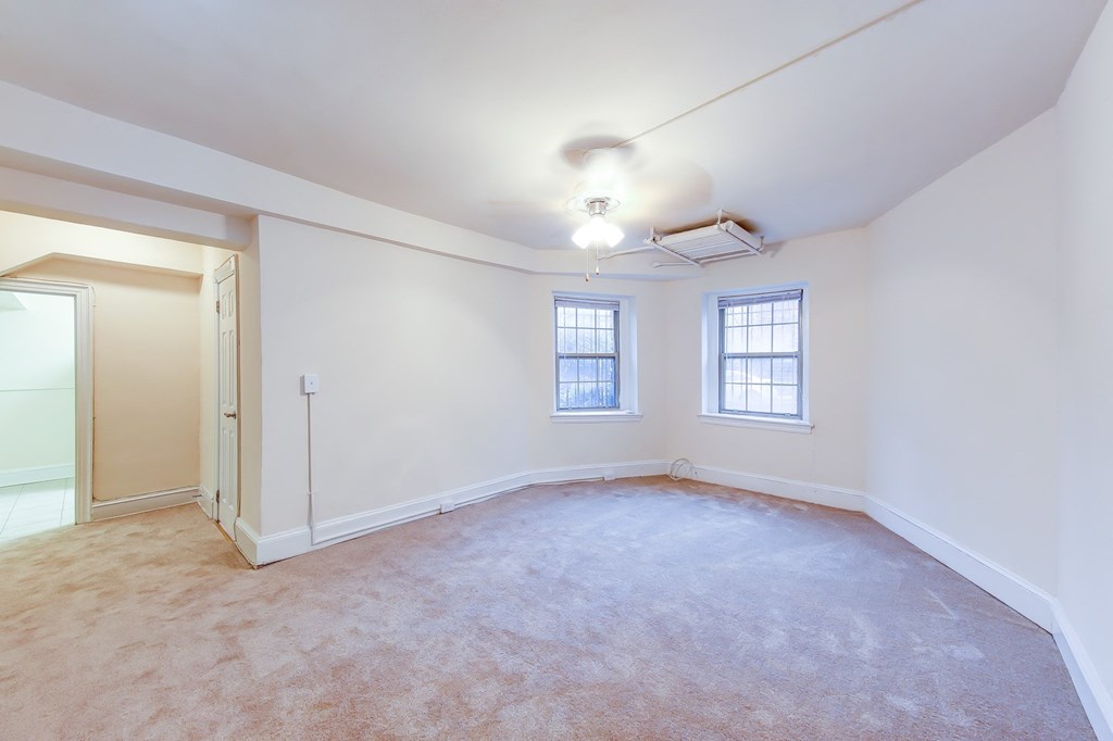 vacant living area with plush carpeting, large windows and ceiling fan at 2800 ontario road apartments in washington dc