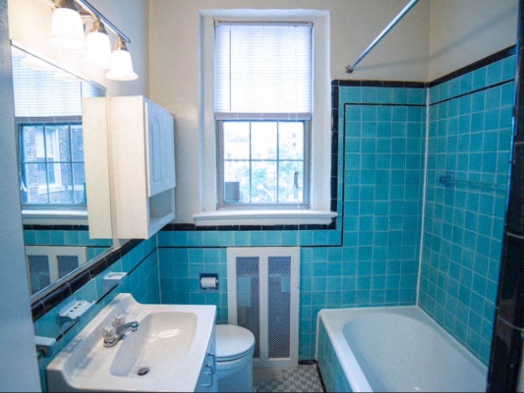 bathroom with tub, vanity, large mirror, tile details and window  at 2800 ontario road apartments in washington dc