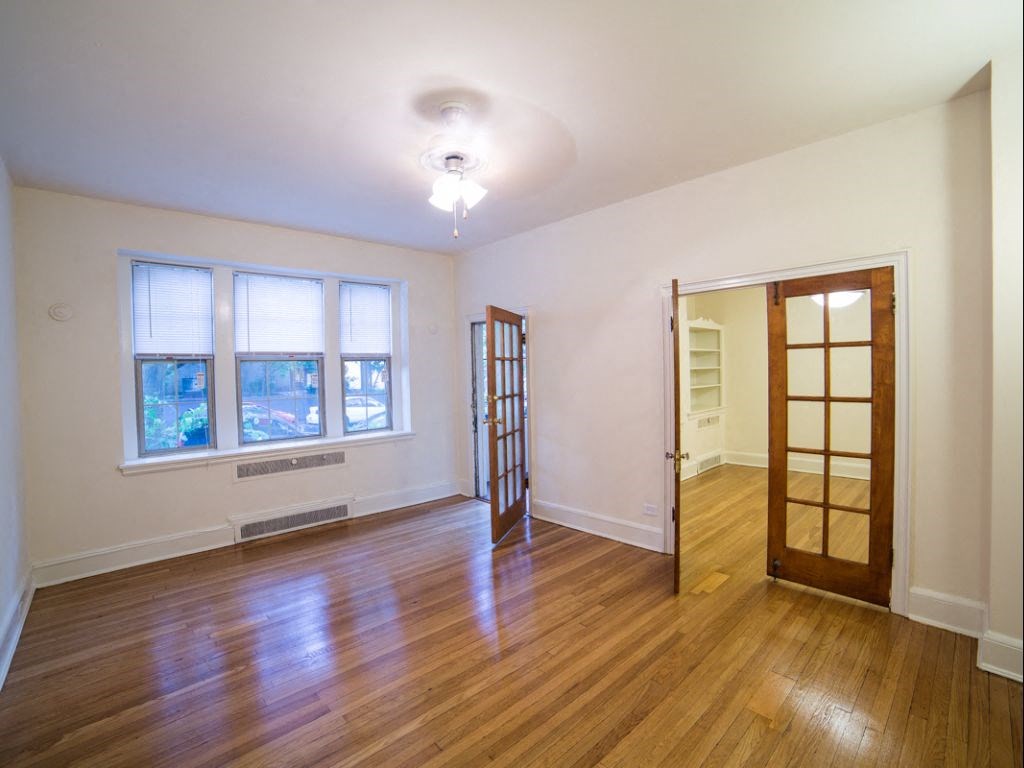 vacant living area with hardwood floors, french doors, large windows and ceiling fan at 2800 ontario road apartments in washington dc