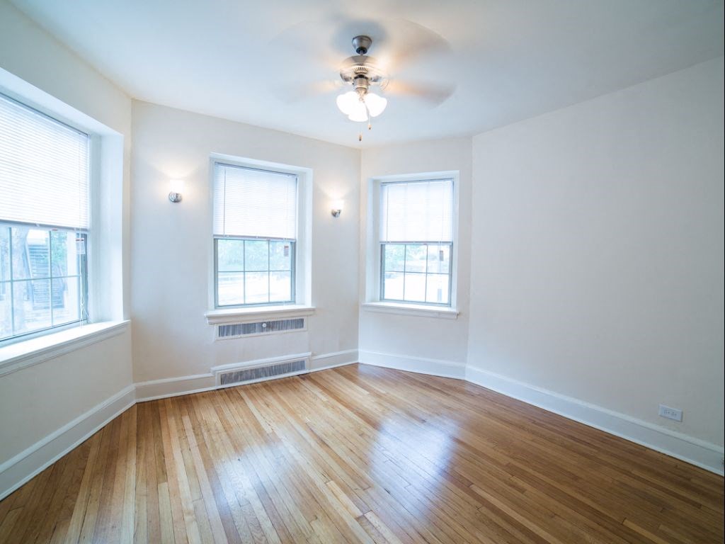 vacant living area with hardwood floors, large windows and ceiling fan at 2800 ontario road apartments in washington dc