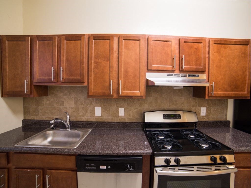 kitchen with dark wood cabinetry, gas range and tile backsplash  at 2800 ontario road apartments in washington dc