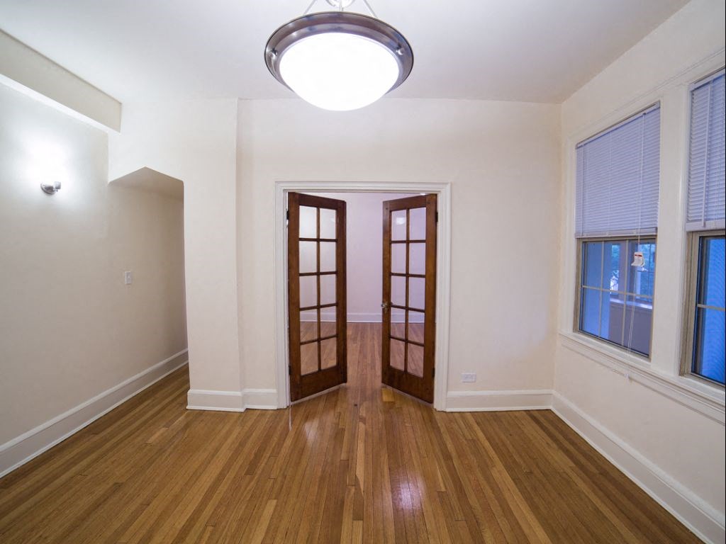 vacant living area with modern lighting, hardwood flooring, large windows and french doors at 2800 ontario road apartments in washington dc