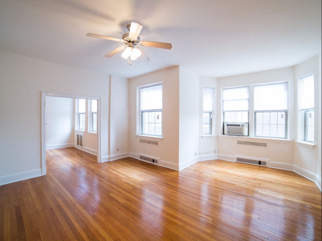 vacant living area with hardwood floors, large windows and ceiling fan at 2800 ontario road apartments in washington dc