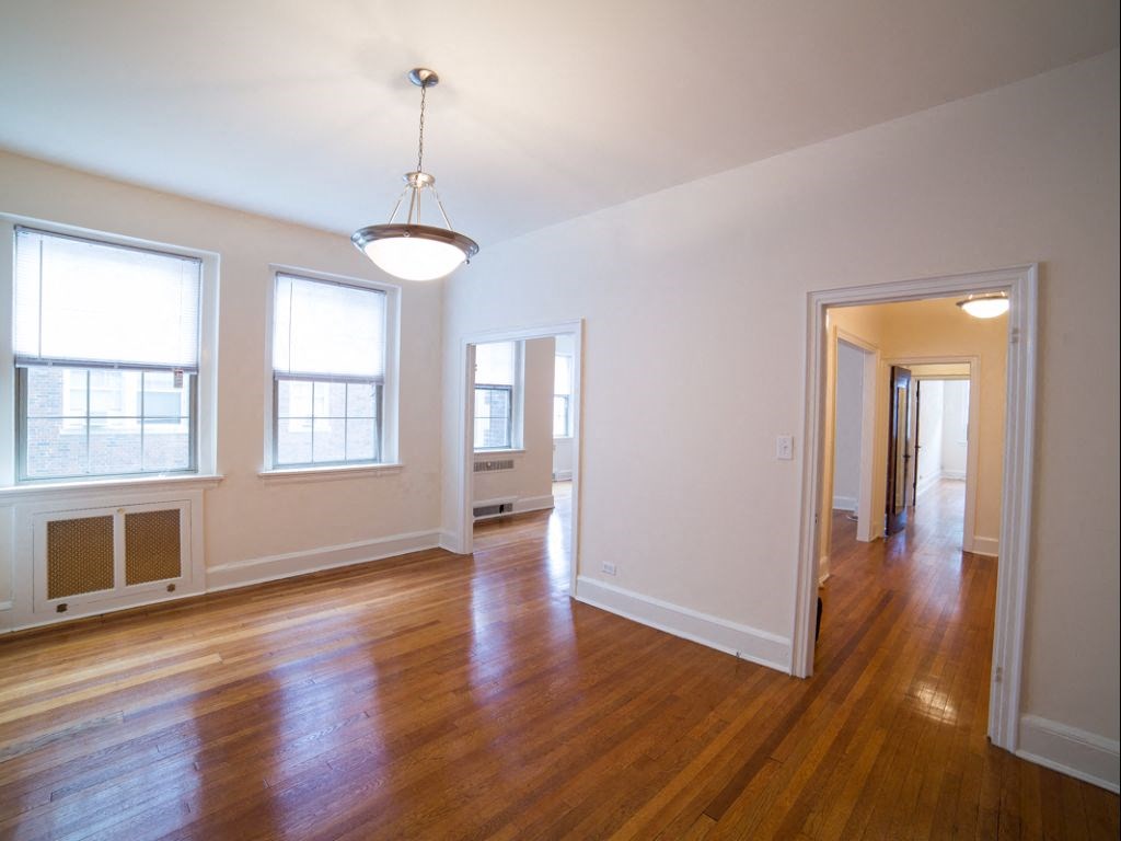vacant living area with modern lighting, hardwood flooring, large windows and french doors at 2800 ontario road apartments in washington dc