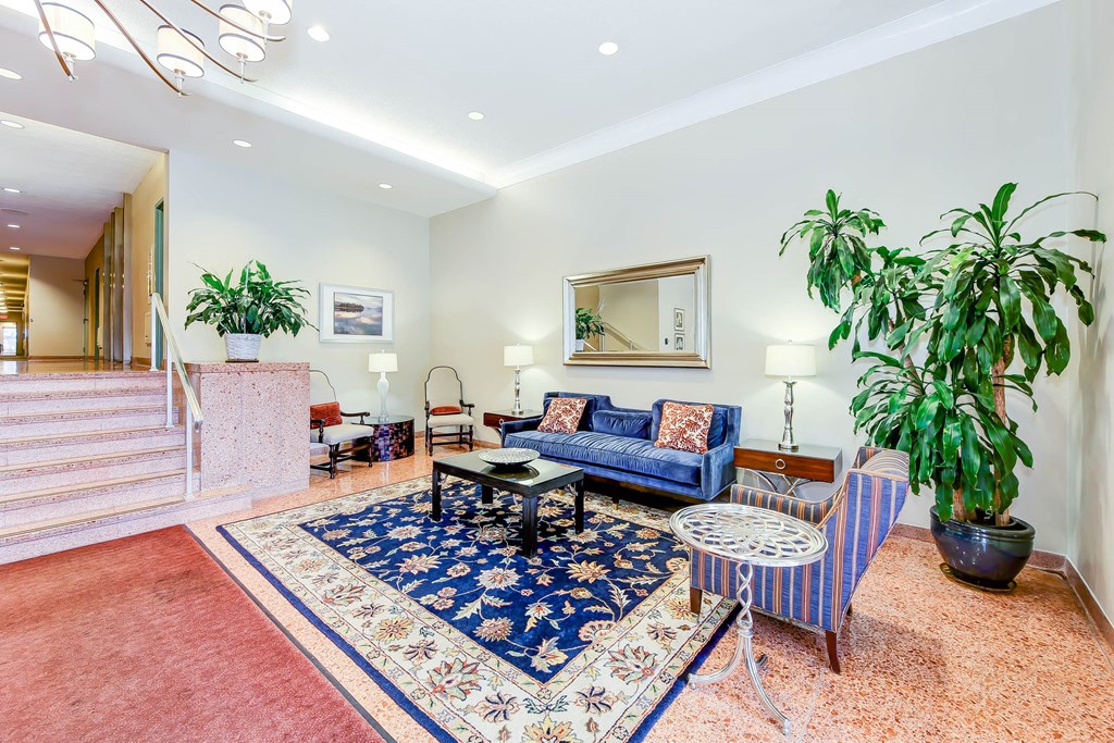 lobby lounge with social seating, large plants and stairs leading to elevators at clarence house apartments in van ness washington dc