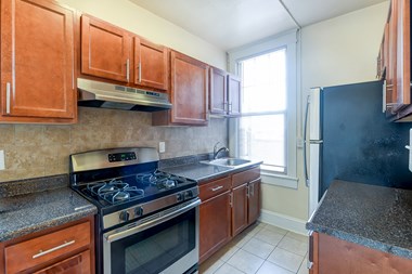 kitchen with tile flooring, wood cabinetry, energy efficient appliances, gas range and window at the cortland apartments in washington dc