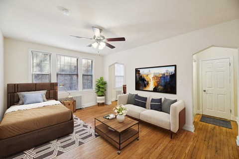 A bedroom with a brown bed and a white couch with a painting on the wall.