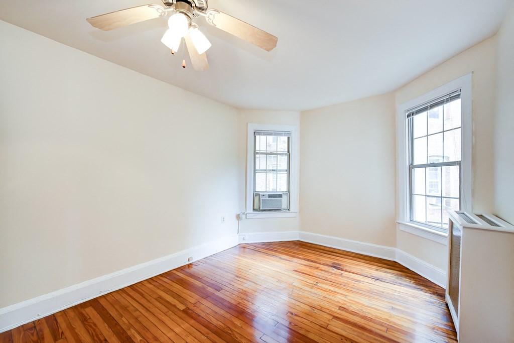 vacant bedroom with hardwood flooring, large windows and ceiling fan at 3151 mount pleasant apartments in washington dc