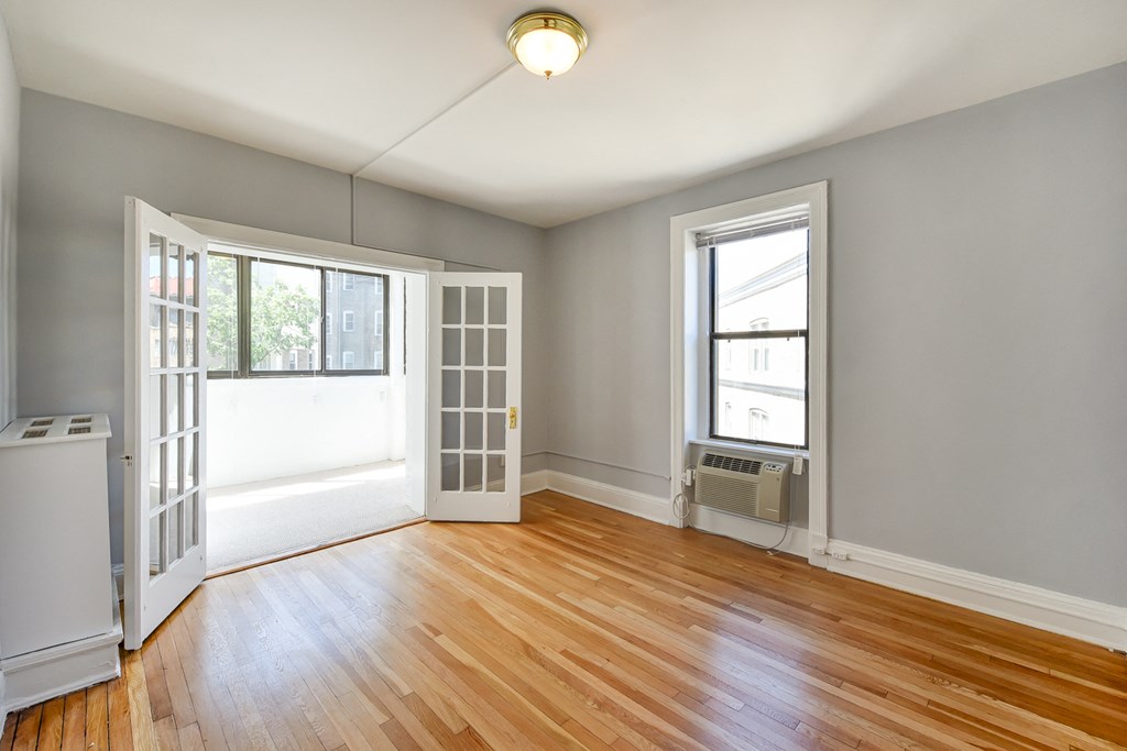vacant living room with view of sunroom french doors, hardwood floors and large windows at the shawmut apartments in adams morgan washington dc