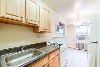 kitchen with gas range, sink, refrigerator and view of dining area at 4031 davis place apartments in washington dc - Photo Gallery 4