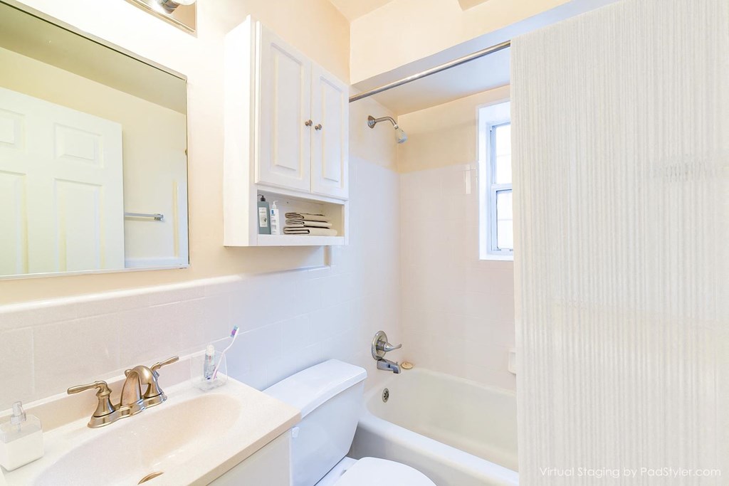 bathroom with toilet, tub, vanity and mirror at 4031 davis place apartments in washington dc