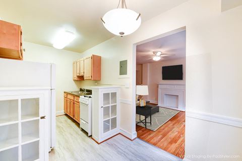 kitchen with gas range, wood cabinetry and view of living area at 4031 davis place apartments in washington dc