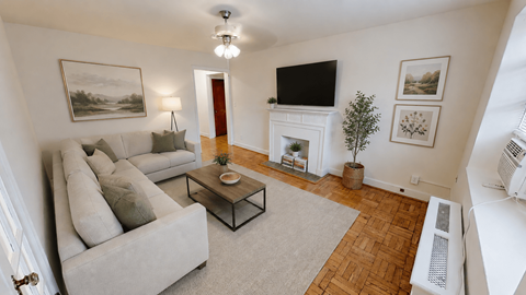 A living room with a grey couch, a coffee table, a fireplace, and a painting on the wall.