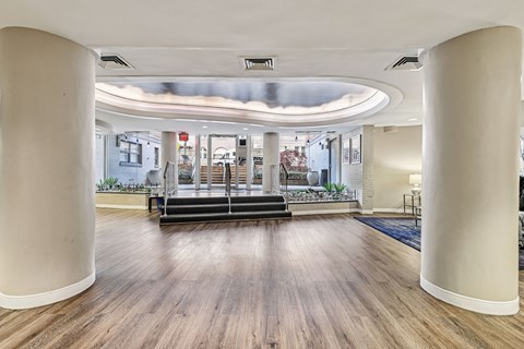 A spacious room with wooden floors and white columns.