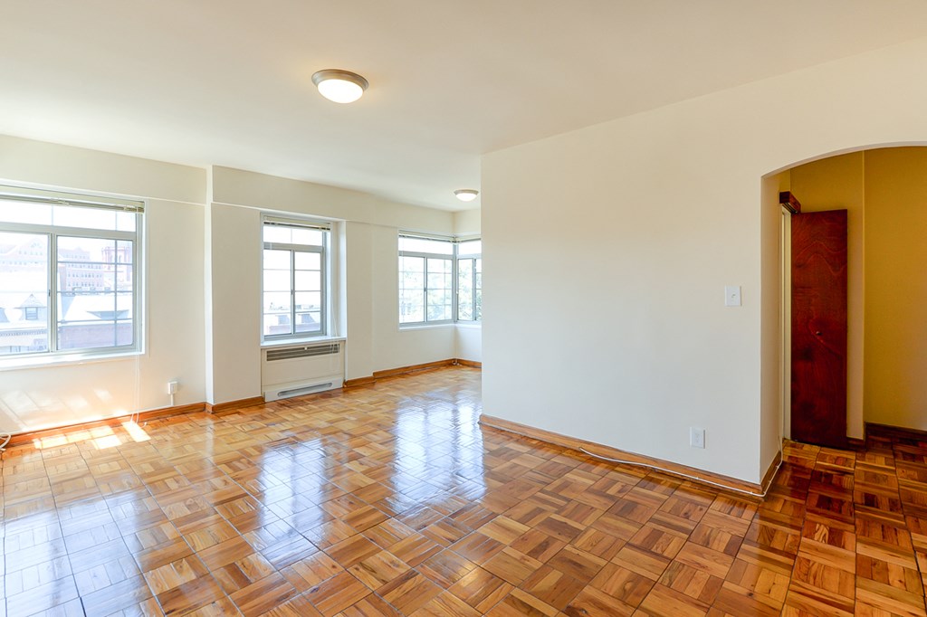 vacant living area with hardwood flooring, large windows and view of entrance at the baystate apartments in washington dc