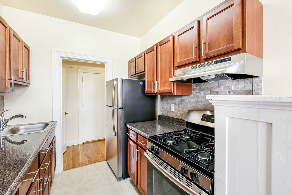 kitchen with stainless steel appliances, tile backsplash and wood cabinets at the frontenac apartments in van ness washington dc