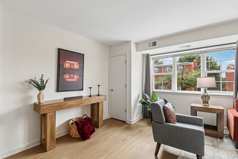 A living room with a grey couch, a wooden bench, and a painting on the wall.