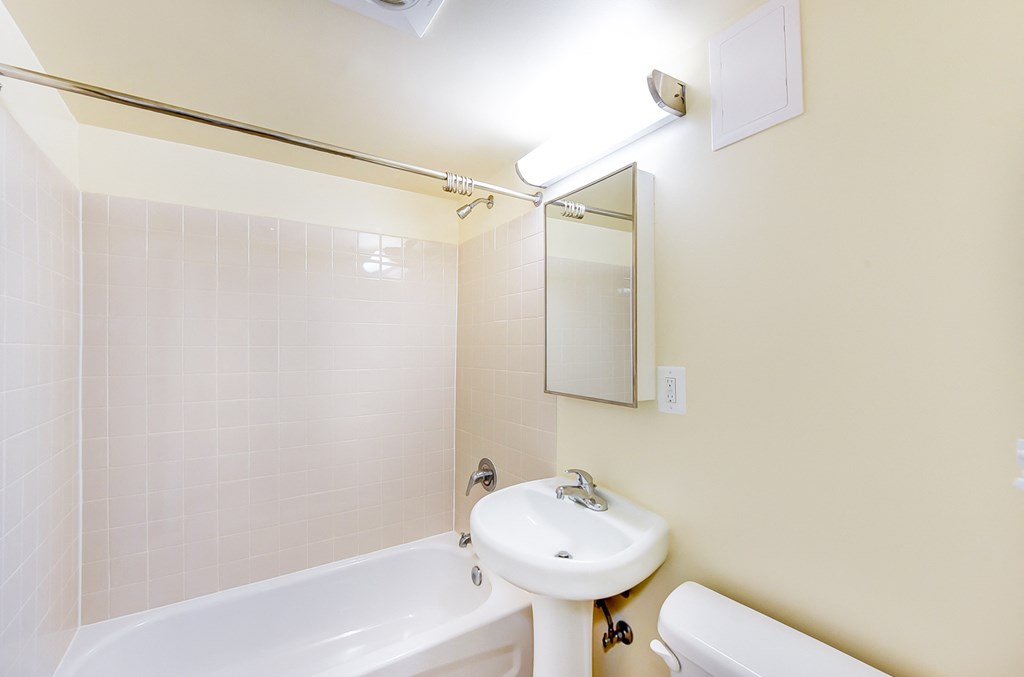 bathroom with toilet, tub, sink and mirror at 734 longfellow street apartments in washington dc