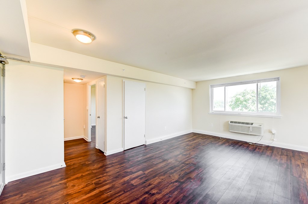 vacant living area with hardwood flooring and large windows at 734 longfellow street apartments in washington dc