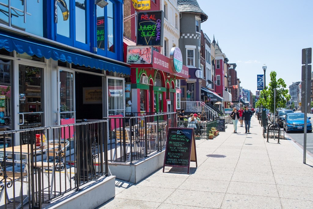A street view of a shopping area with a signboard in the foreground.