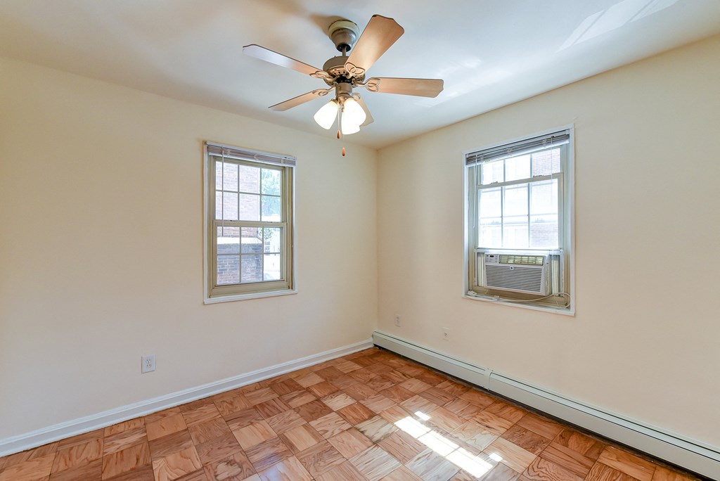 an empty living room with a ceiling fan and two windows