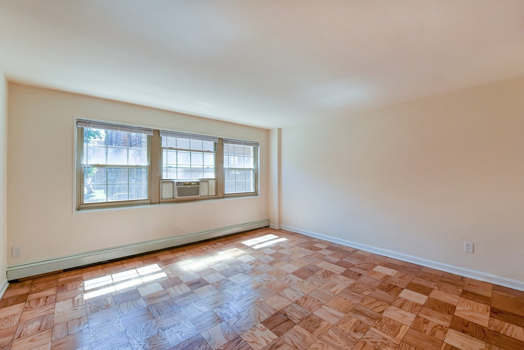 vacant living area with large windows and hardwood floors at alpha house apartments in washington dc